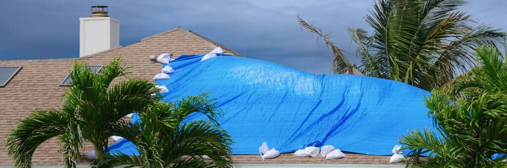 Shingle tile roof with tarp covering damaged section