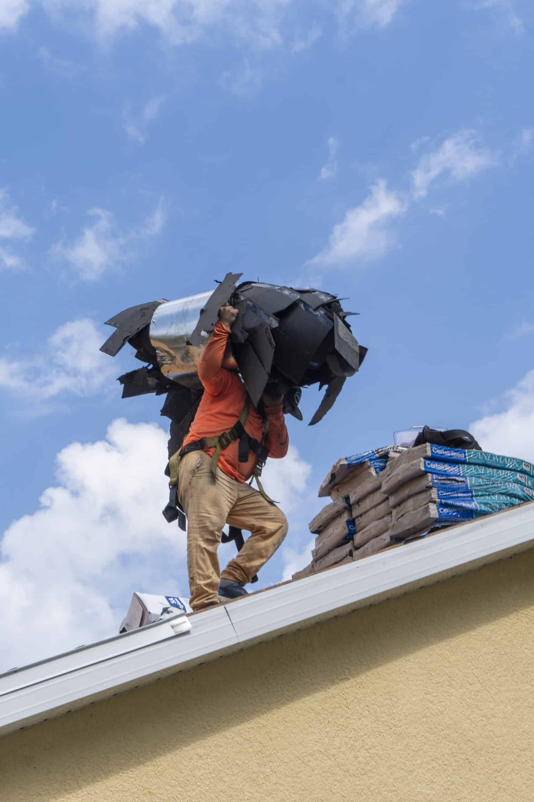 Roofer Carrying Old Asphalt Shingles Off of Roof