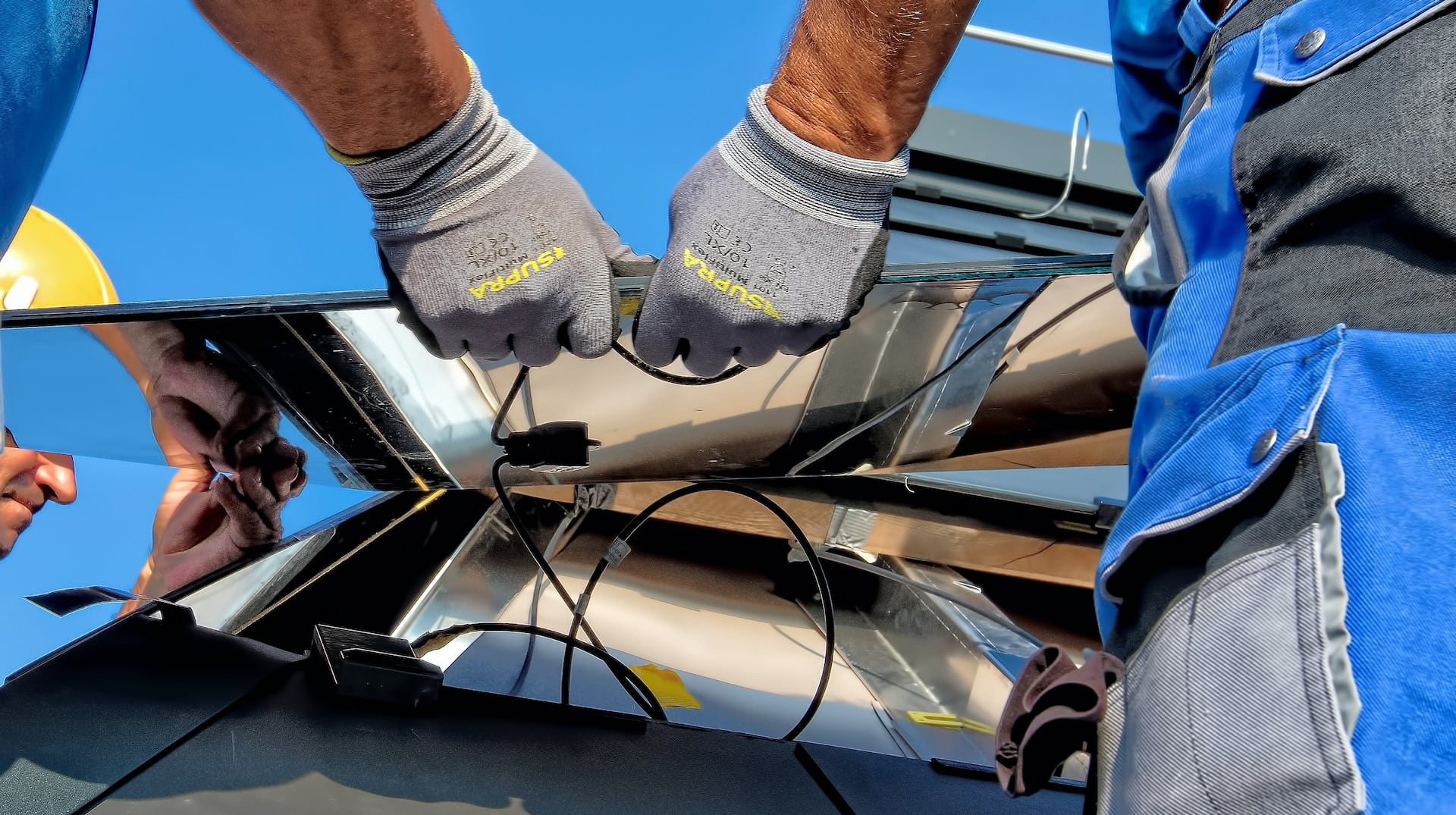 roof installers holding a piece of solar roof and installing it